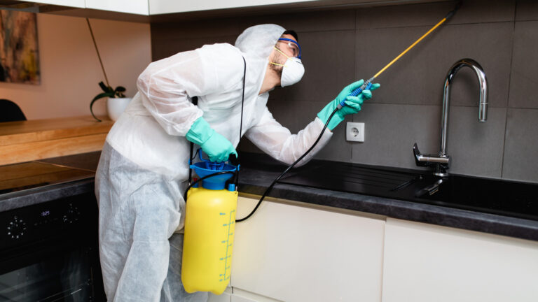 a person wearing protective gear and spraying under the kitchen chimney.