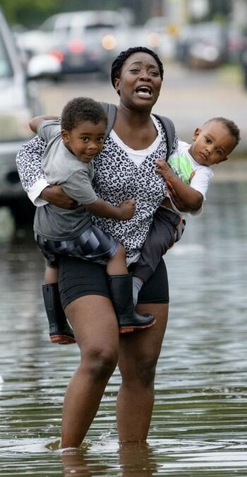 A mother carries her children through flood water